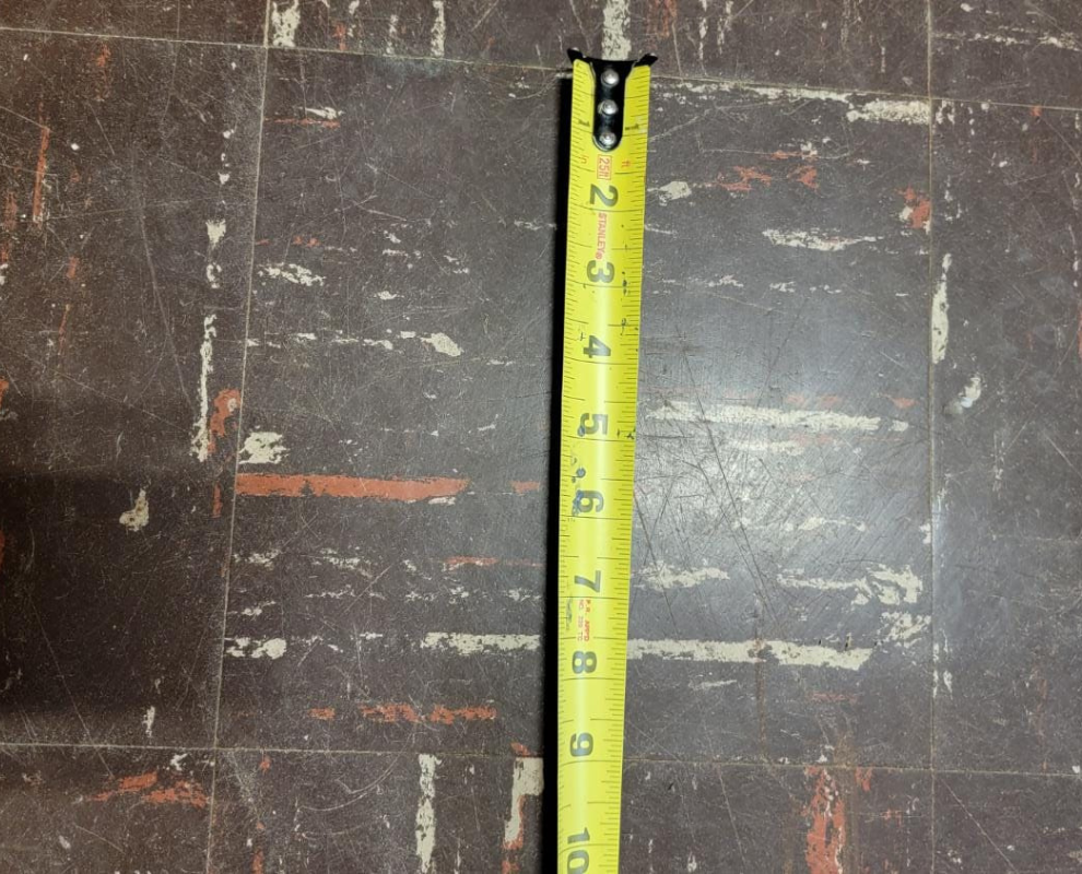 A tape measure highlighting the 9" width of the tile which typically means it contains asbestos.