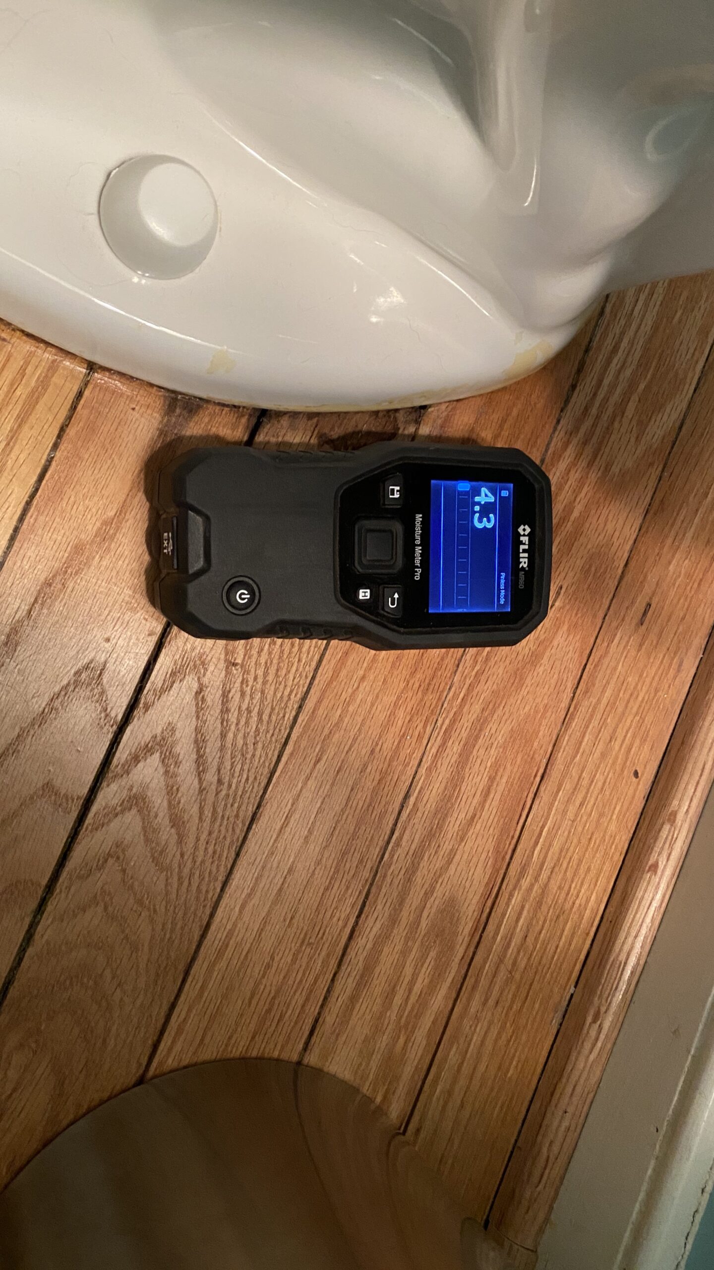 Moisture meter next to the toilet shows that the moisture stains are dry.