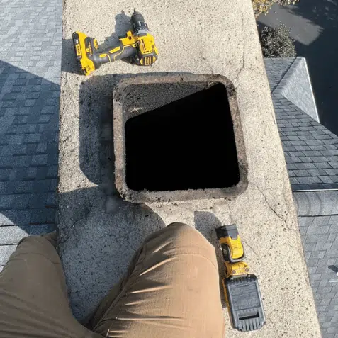 Photo of a home inspector on a chimney looking down into the chimney